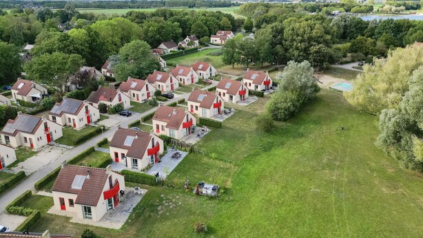 Een woonwijk met huizen, groene gazons en een klein vijver.
