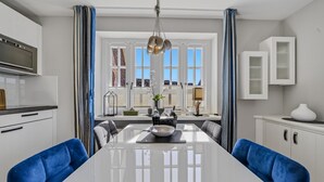 Une cuisine moderne avec un îlot central, des meubles blancs et des chaises bleues.