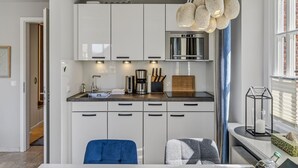 Une cuisine moderne avec des armoires blanches, une hotte de cuisinière en acier inoxydable et un four encastré.