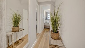 Un couloir doté d’un plancher en bois, de murs blancs et de deux paniers en osier contenant des plantes.