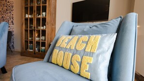 Ein blauer Sessel mit einem Kissen, auf dem 'BEACH HOUSE' steht.