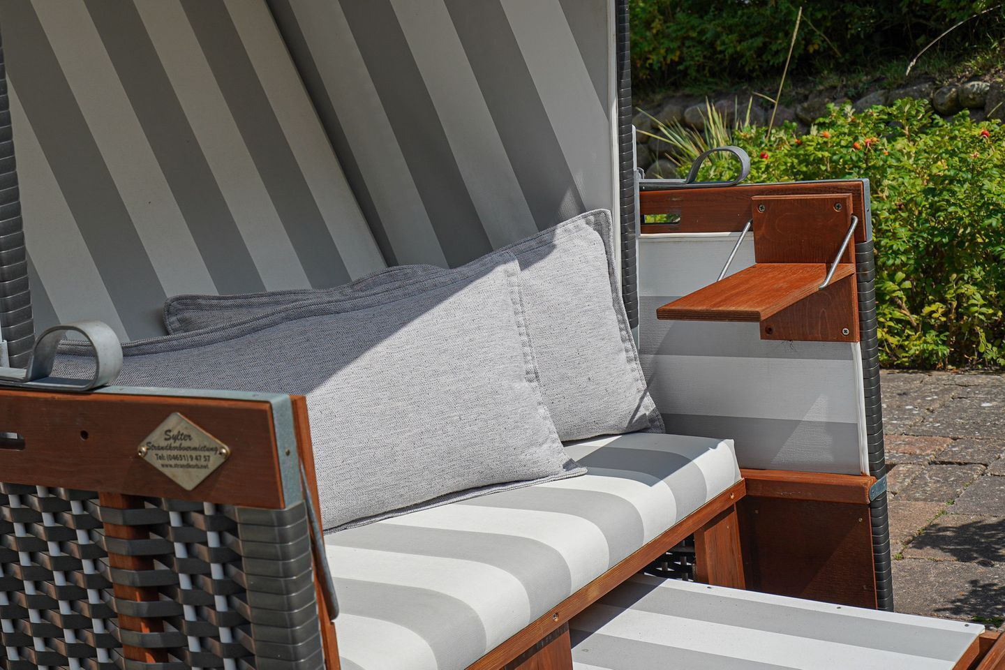A sun lounger with a cushion, a small wooden table, and a metal frame.
