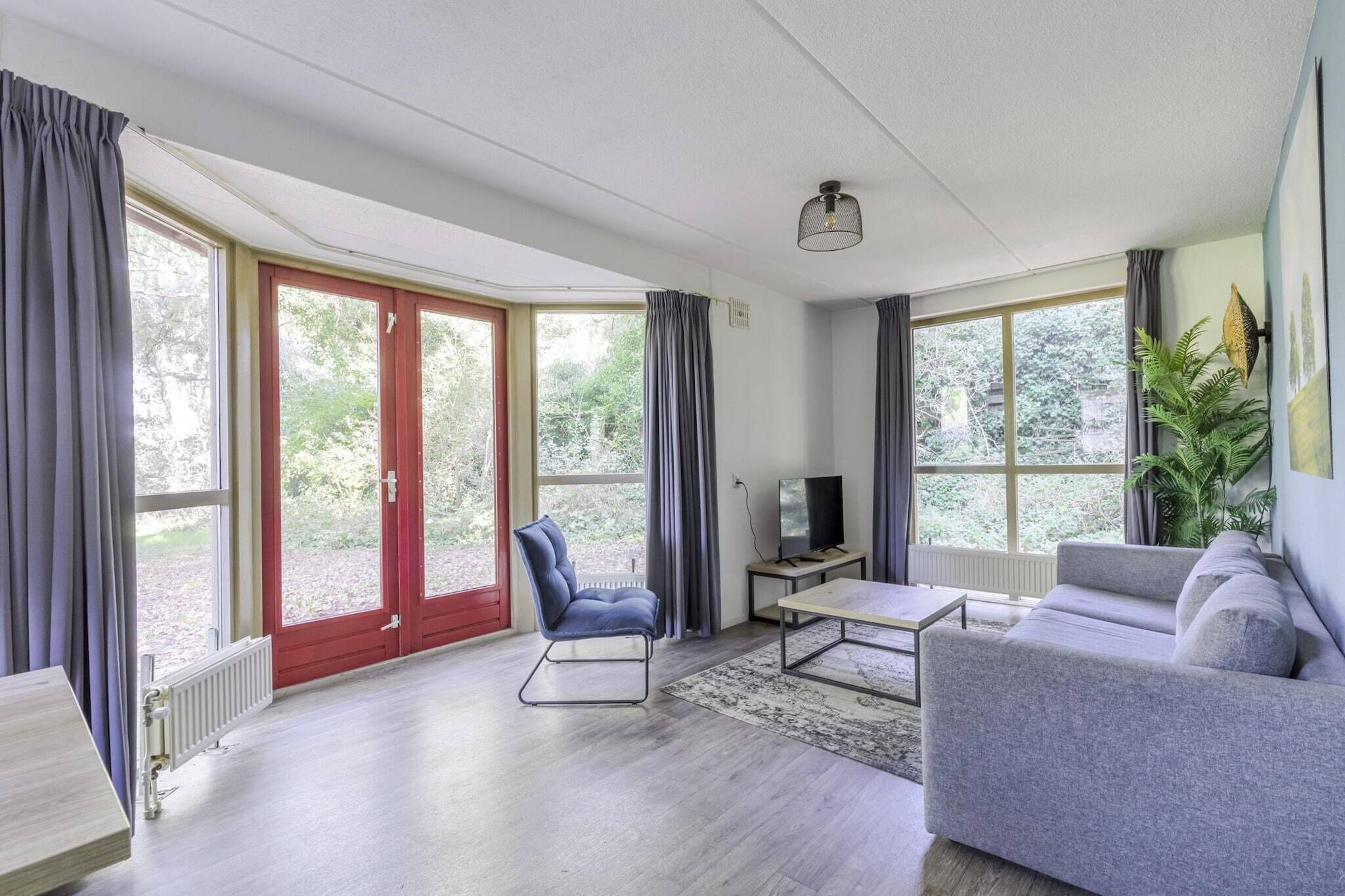 Ein modernes Wohnzimmer mit einer Couch, einem Sessel, einem Couchtisch und einem Fernseher.