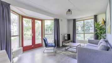Ein modernes Wohnzimmer mit einer Couch, einem Sessel, einem Couchtisch und einem Fernseher.