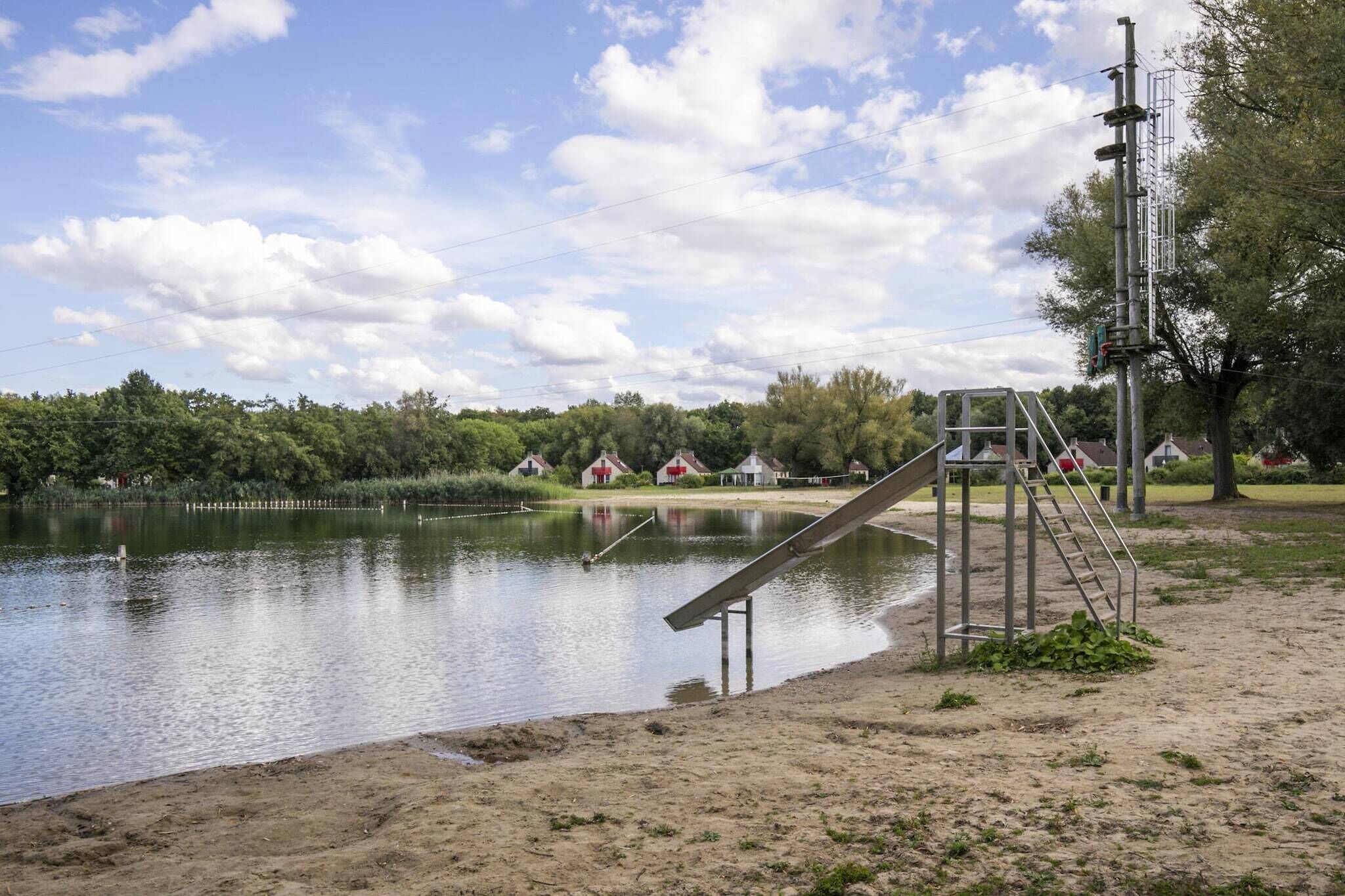 A lakeside area with a metal slide, a ladder, and a wooden structure.