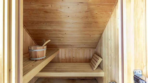 A wooden sauna with benches and a bucket.
