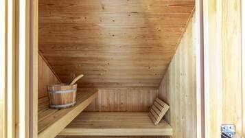 A wooden sauna with benches and a bucket.