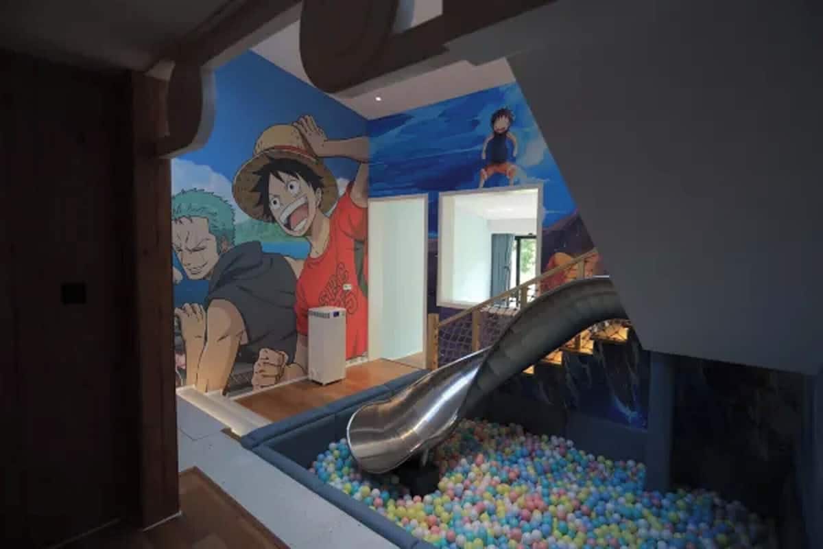 A children's play area with a slide and ball pit, featuring a mural of animated characters.