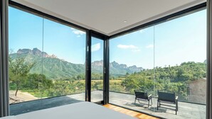 A room with large windows, a bed, and two chairs. - Manning Retreat (Handan)