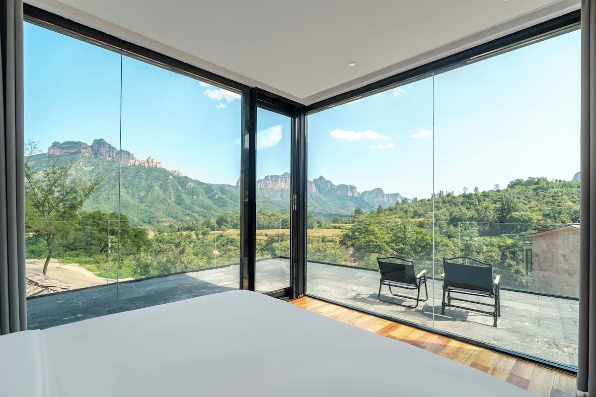 A room with large windows, a bed, and two chairs.