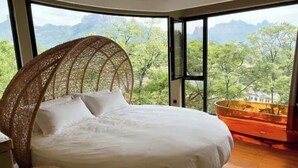 A bed with a view of trees and mountains through large windows. - Manning Retreat (Handan)