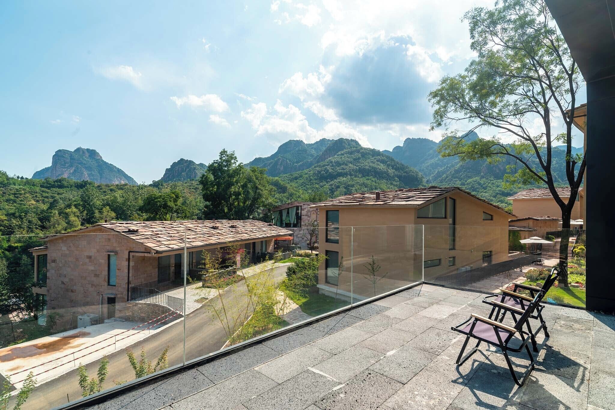 Un edificio moderno con balcón de vidrio que da a un paisaje montañoso.
