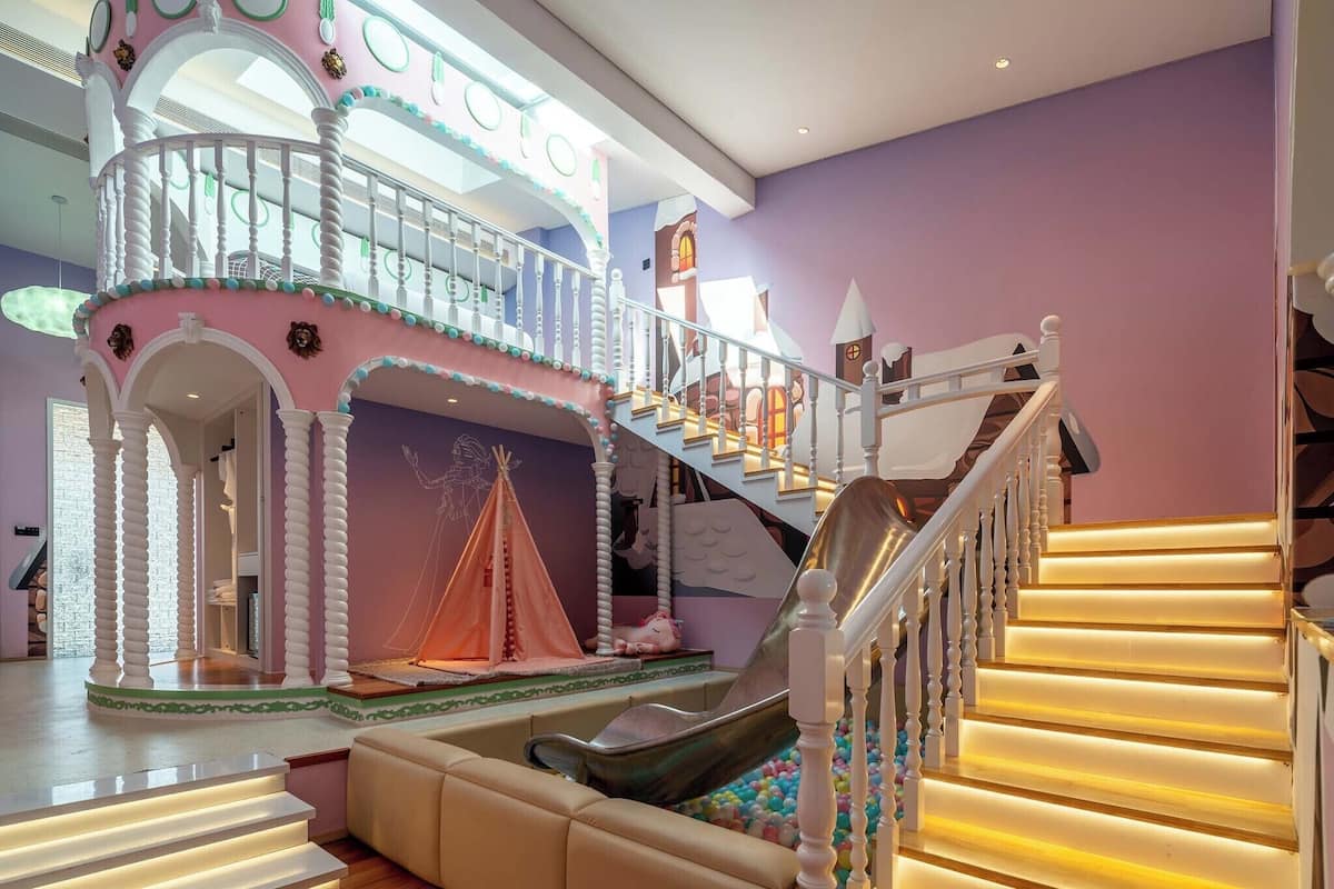 A multi-level indoor play area with a slide, a cushioned seating area, and a staircase.