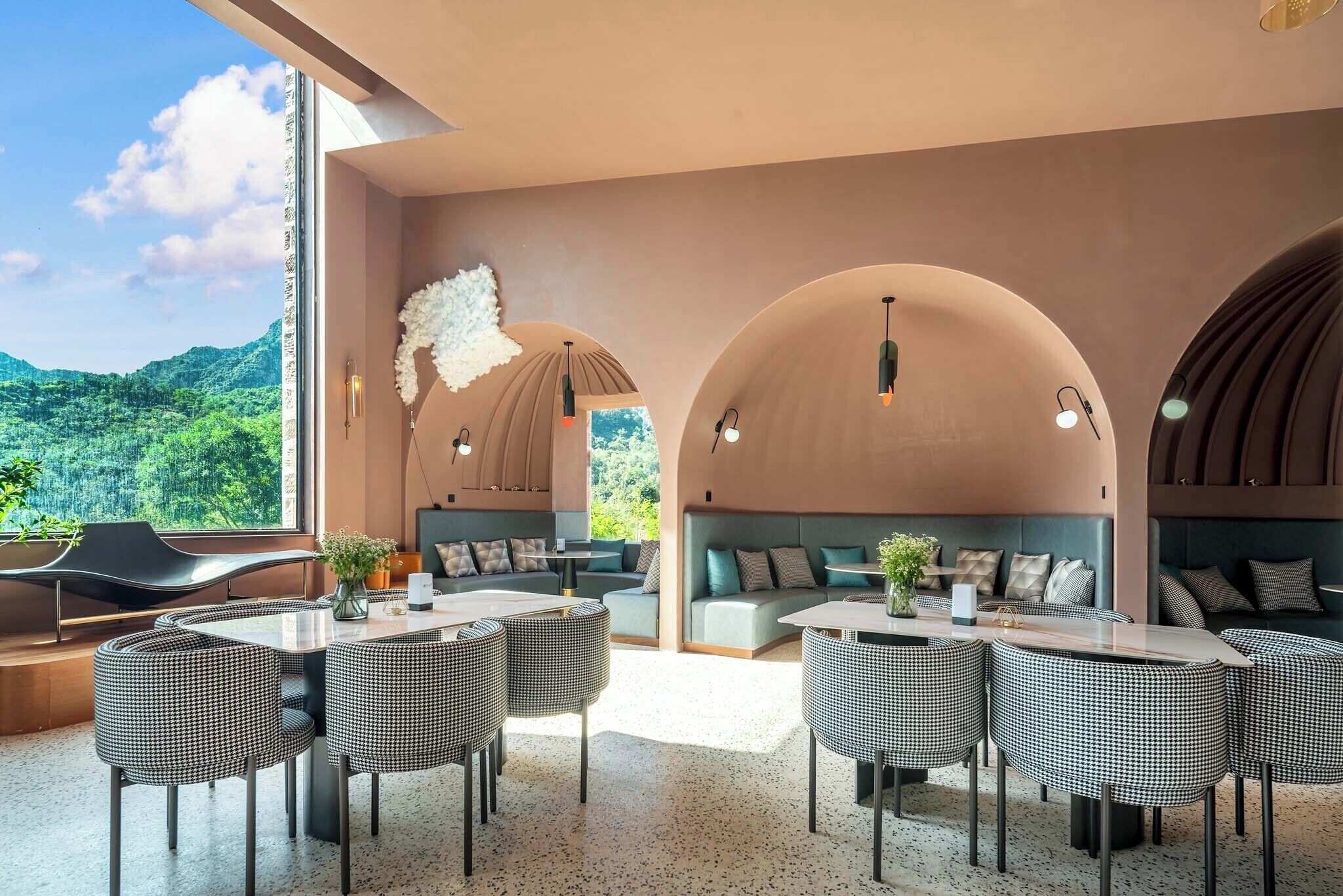 A modern dining area with checkered chairs, a long table, and a view of lush greenery.