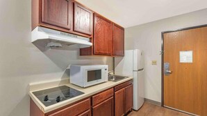 Una pequeña cocina con armarios de madera, un microondas, un refrigerador y un lavamanos.