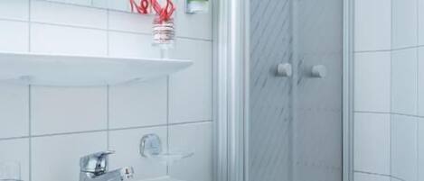 A bathroom with a white sink, a glass shower enclosure, and a tiled floor.