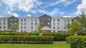 Ein mehrstöckiges Hotel mit einem zentralen Eingang, einem Parkplatz und gepflegter Bepflanzung.
