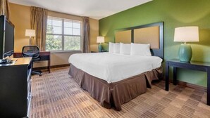 Una habitación de hotel con una cama grande, un escritorio, una silla, un televisor y dos lámparas.