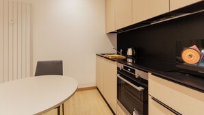 Moderni keittiö, jossa on pyöreä pöytä, sisäänrakennettu uuni ja kahvinkeitin.