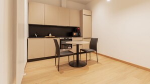 Moderni keittiö, jossa on pyöreä ruokapöytä ja -tuolit, sisäänrakennettu uuni ja kahvinkeitin.
