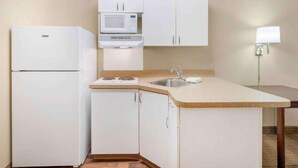 A compact kitchen with a refrigerator, microwave, sink, and a small countertop.