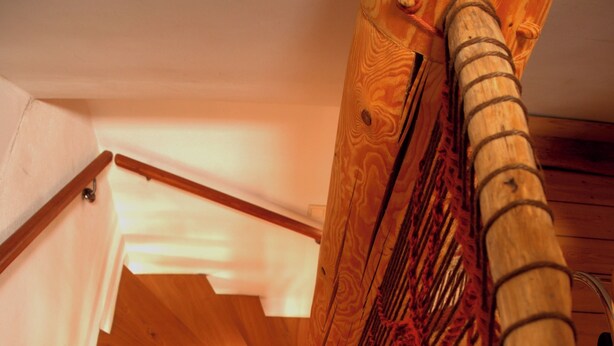 Eine Holztreppe mit Handlauf und einer gewebten Stoffverkleidung.
