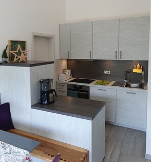 Eine moderne Küche mit grauen Schränken, einer Kaffeemaschine, einem Toaster und einer Spüle.