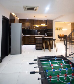 Una cocina moderna con comedor, mesa de fútbol y una escalera que sube a otro nivel.