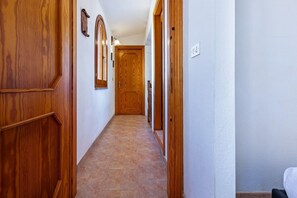 A hallway with wooden doors, a tiled floor, and a light switch on the wall. - Elegant and welcoming 70 square meters townhouse, perfect for six people, with a private entrance and spread over two floors.The property is located in Villasimius, a town known for its splendid sandy beaches and crystal-clear sea. The apartment is centr (Villasimius)