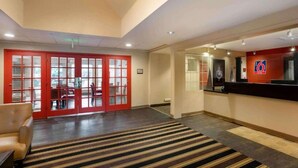 Un vestíbul d'hotel amb una recepció, una zona de seients i una escala.