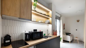 A modern kitchen with a wooden countertop, black appliances, and a white tiled backsplash. - Oraya Chic Studio with Balcony in Athens (Athens)