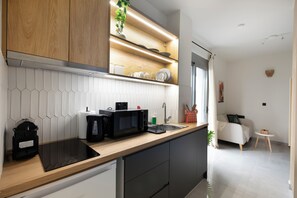 A modern kitchen with a wooden countertop, black appliances, and a white tiled backsplash.