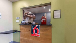 Un comptoir d’accueil avec une pancarte indiquant « 6 suites », un ordinateur et un extincteur.