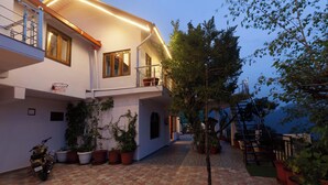 A two-story building with a balcony, potted plants, a staircase, and a tiled courtyard. - Alaya Stays Amara Dawn (Naina Range)