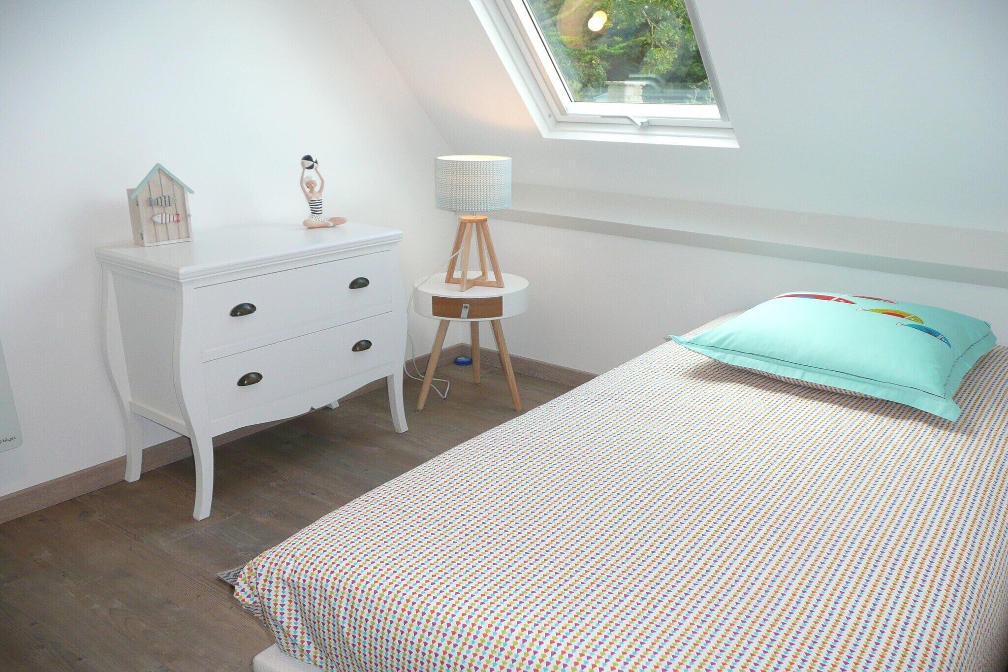 A bedroom with a bed, a dresser, a lamp, and a window.