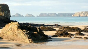 Une plage rocheuse avec une eau claire et des falaises qui se dressent au loin.
