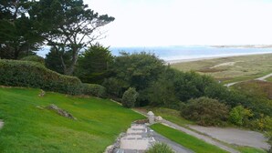 Un chemin de pierres qui mène à une zone herbeuse offrant une vue sur la mer.
