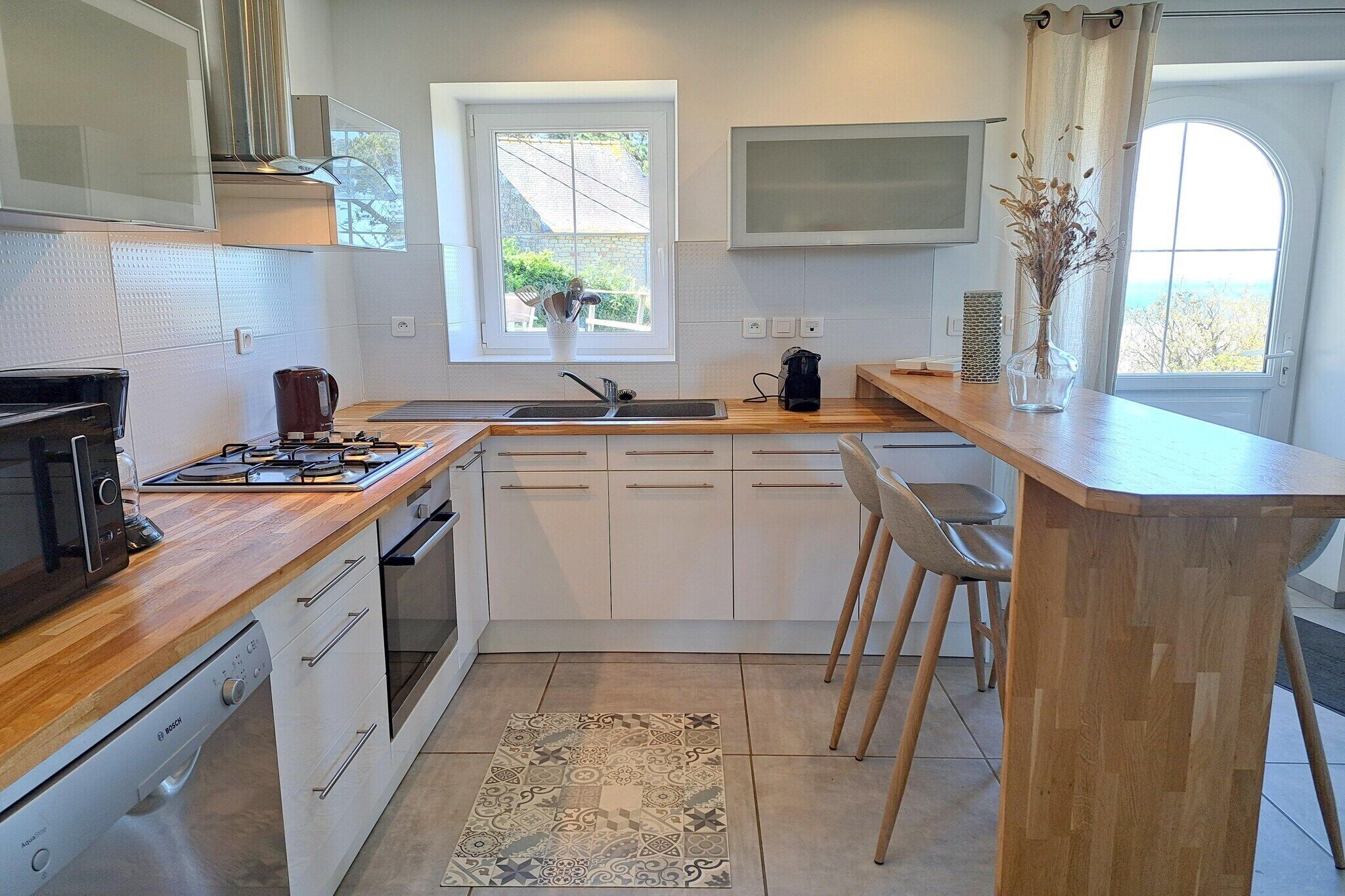 A modern kitchen with white cabinets, a built-in oven, a microwave, and a coffee maker.