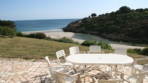 A patio with a round table and chairs overlooking a beach. - Spacious Coastal Villa near Rospico Beach (Nevez)