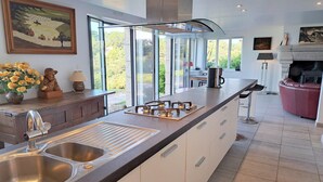 A modern kitchen with a large island, stainless steel sink, and a fireplace. - Spacious Coastal Villa near Rospico Beach (Nevez)