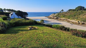 A coastal property with a grassy area, a paved path, and a building with a sign. - Spacious Coastal Villa near Rospico Beach (Nevez)