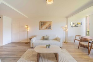 A living room with a sofa, coffee table, floor lamp, and a dining table. - Magnificent Appartment - 6P - Saint Tropez Center (Saint-Tropez)