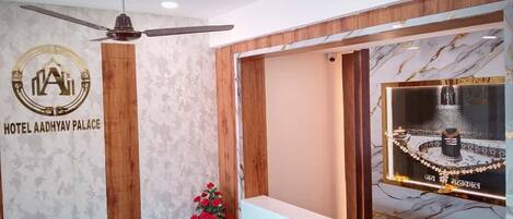 A reception area with a ceiling fan, a reception desk, a wall-mounted logo, and a decorative window.