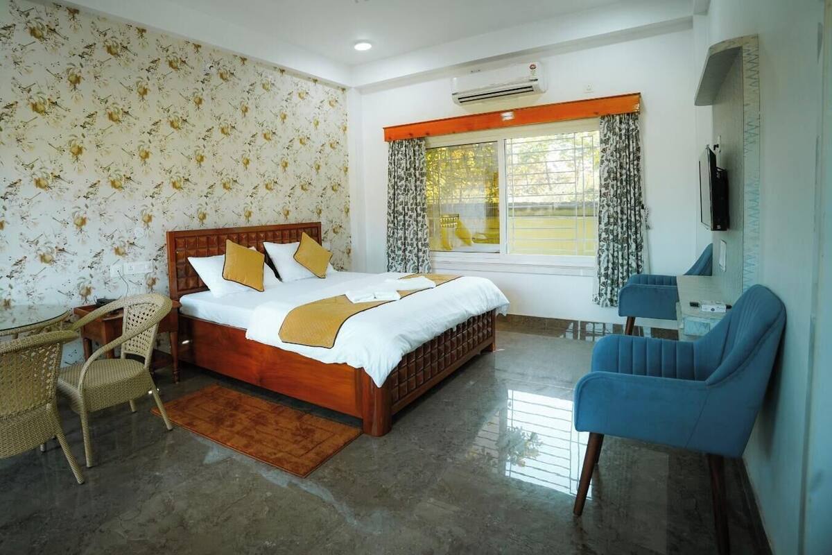 Un dormitorio con cama, escritorio, silla, televisión y ventana con cortinas.