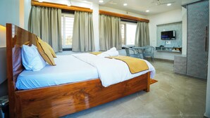 A hotel room with a wooden bed, a desk, a television, and a wardrobe. - Jai Ganesha Resort (Mal)
