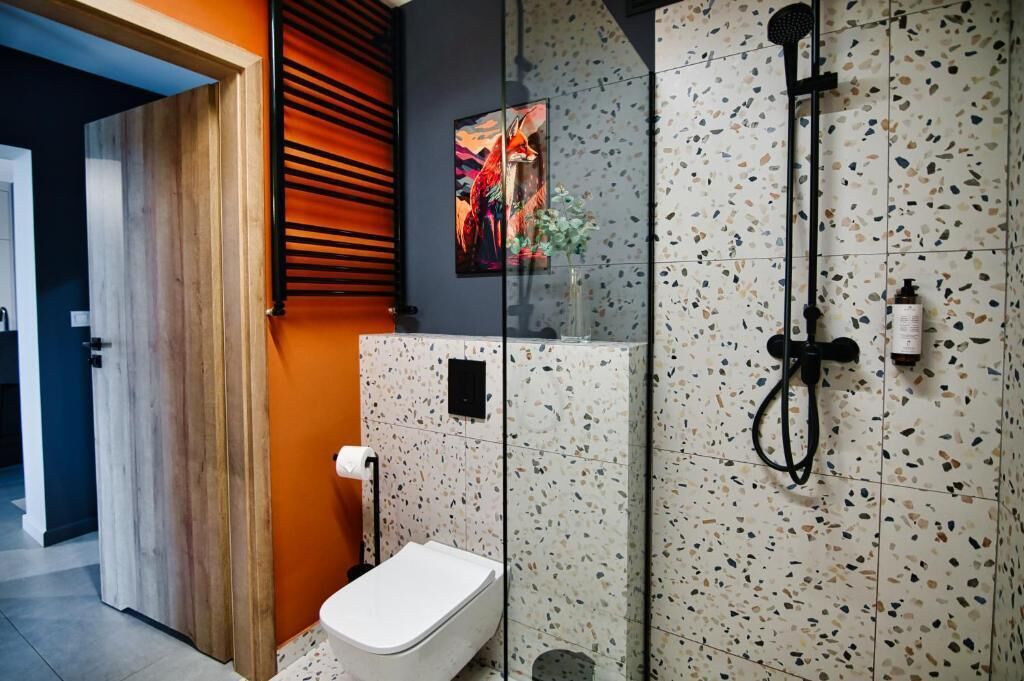 A modern bathroom with a shower, toilet, and a glass partition.