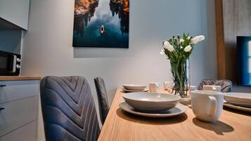 Un comedor con una mesa de madera, sillas, un jarrón con flores y un cuadro en la pared.
