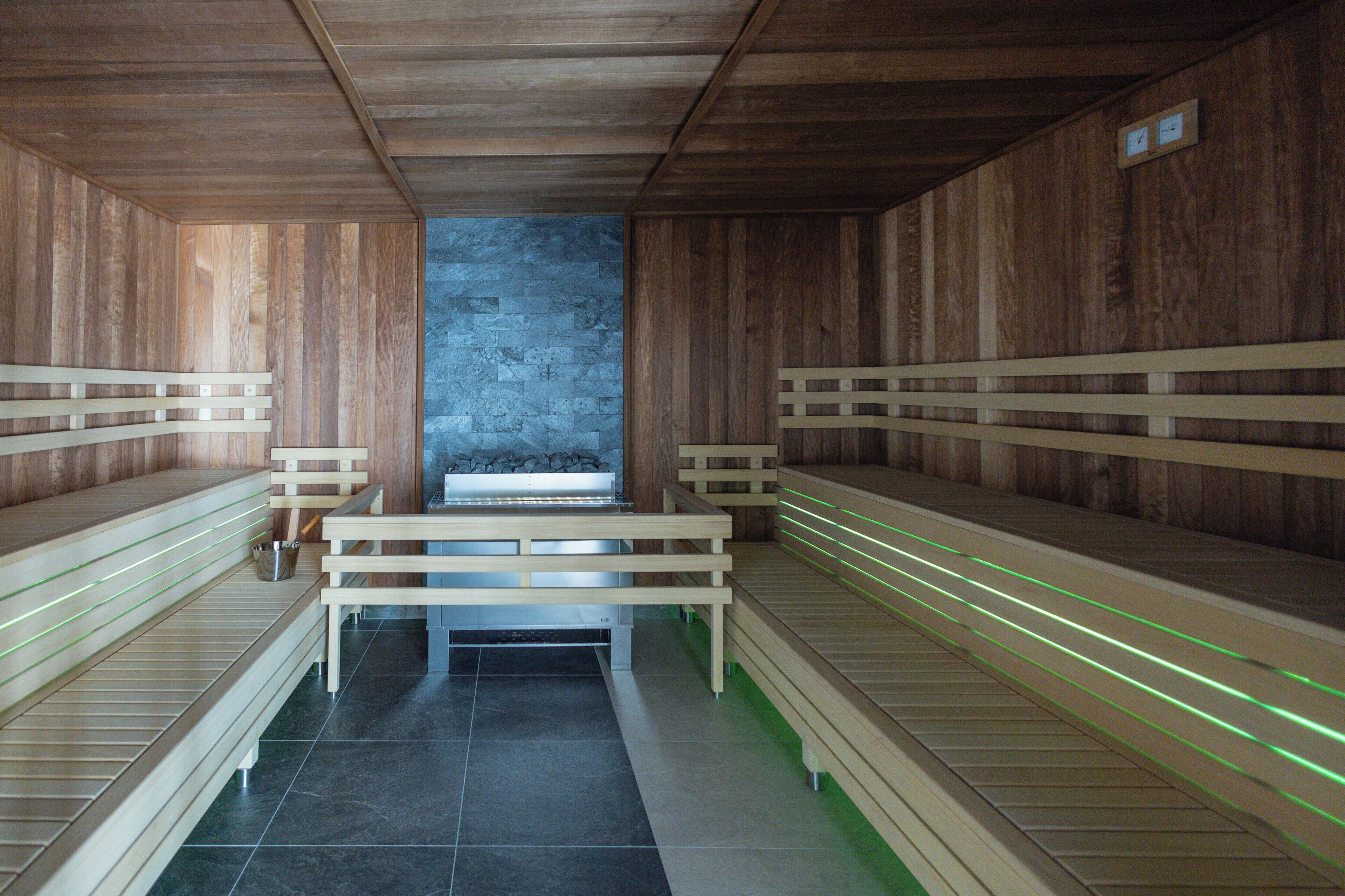 Una sauna con bancos de madera y una pared de piedra.