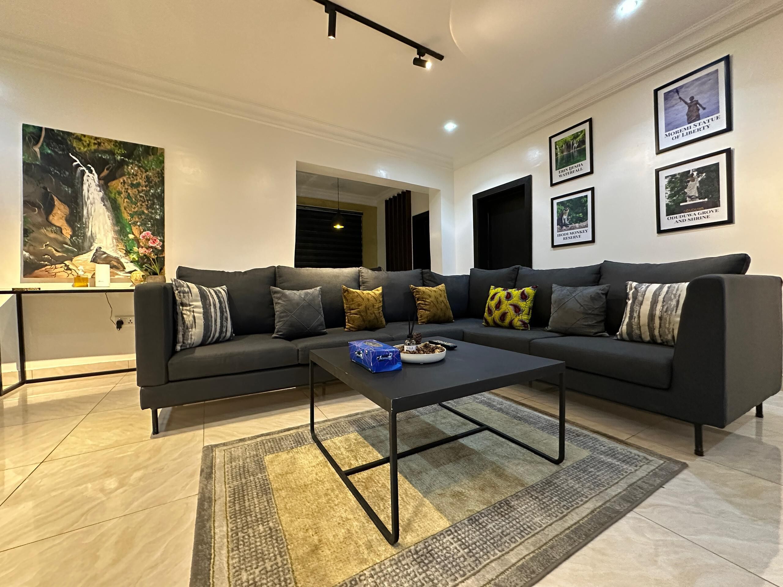 A modern living room with a sectional sofa, a coffee table, and framed artwork on the walls.