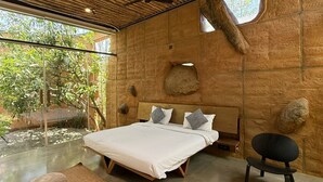 Une chambre moderne avec un grand lit, un petit coin salon et une vue sur la verdure environnante.